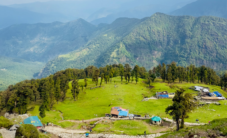 Breathtaking view of Chopta Valley with lush green meadows, dense forests, and Himalayan peaks in the backdrop