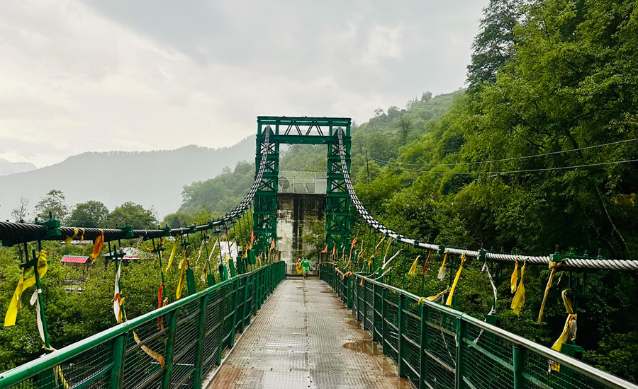 Iron bridge leading to Kalpeshwar Temple, surrounded by dense forest and Himalayan silence