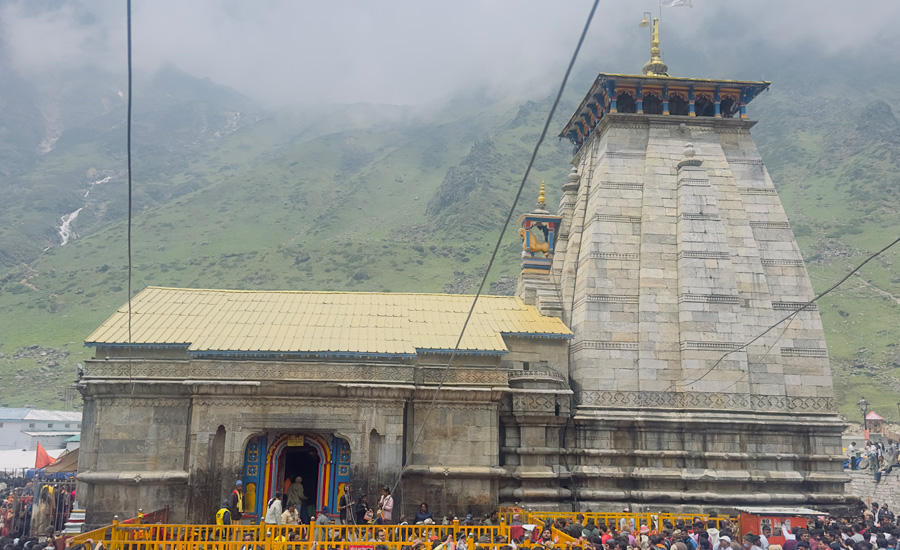 First side glimpse of Kedarnath Temple appearing through the mist—an emotional moment of arrival after the long Himalayan ascent
